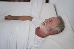 Older man lying awake in bed, staring at the ceiling, a common sign of sleep problems in older adults
